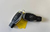 Zwei Mercedes-Benz Autoschlüssel und ein gelber Anhänger auf weißem Hintergrund.
