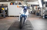 Frontansicht eines weißen elektrischen Rollers in einem Showroom.