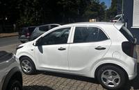 Weiße KIA Picanto Seitenansicht vor einem Autohaus.