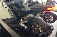 Seitenansicht eines blauen ZERO Motorrads, das auf einem schwarzen Teppich in einem Showroom steht.