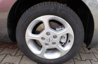 Nahaufnahme des silbernen Leichtmetallfelges mit Reifen an der Seite eines grauen Nissan Leaf.