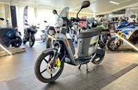 Ein elektrischer Roller in matt metallic titanium steht in einem Showroom.