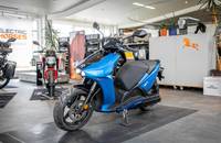 Seitenansicht eines blauen Elektrorollers (RAY 7.7) in einem Autohaus.