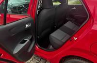 Offene Fahrertür eines roten Autos, Blick auf den schwarzen Innenraum und die Sitze.