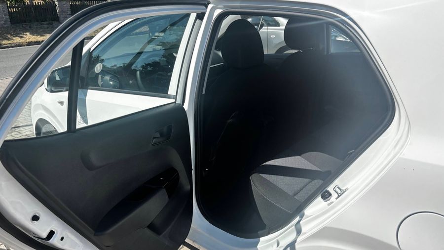 Die offene Fahrertür eines weißen KIA Picanto zeigt den Innenraum.
