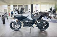 Silbernes Elektro-Motorrad (ZERO) in einer Dreiviertel-Ansicht, das in einem hellen Showroom ausgestellt ist.