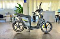 Seitenansicht eines modernen, elektrischen Scooters in matt metallic titanium an einem hellen Showroomboden.