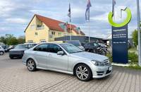Außenansicht eines silbernen Mercedes-Benz C-Klasse vor einem Autohaus.