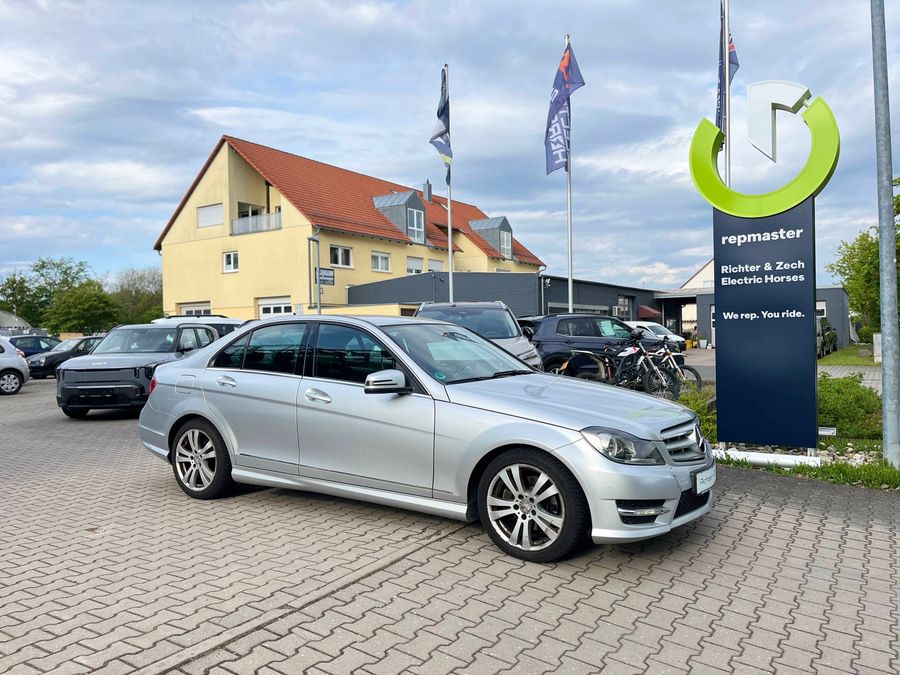 Außenansicht eines silbernen Mercedes-Benz C-Klasse vor einem Autohaus.
