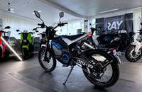 Ein blaues Elektro-Motorrad (VMOTO ON-R) steht in einem hellen Showroom.