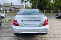 Heckansicht eines silbernen Mercedes-Benz auf einem Parkplatz vor einem Autohaus.