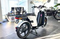 Außenansicht eines weißen, elektrischen Rollers, der in einem hellen Showroom steht.