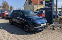 Dunkelblauer Nissan Micra EV auf einem Parkplatz vor dem Autohaus.