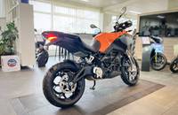 Eine orangefarbene Motorrad ist in einem Showroom auf einem grauen Boden abgestellt.