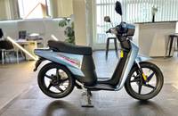 Seitenansicht des blauen E-Scooters auf einem Fliesenboden.