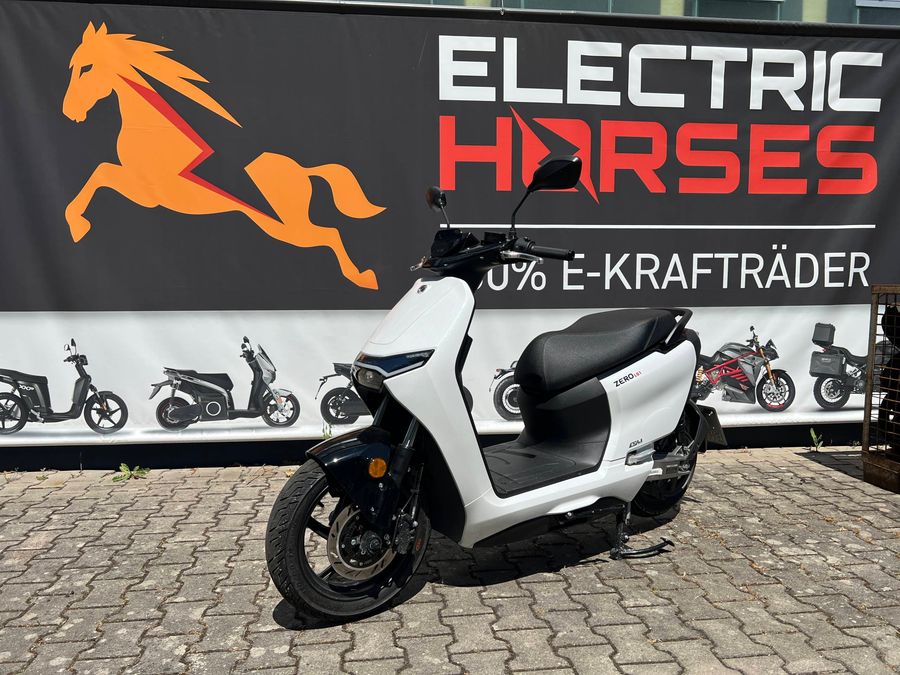 Außenansicht eines weißen Elektrorollers (ZERO) vor einem Werbebanner.