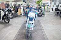 Silbernes E-Motorrad wird in einem hellen Showroom präsentiert.
