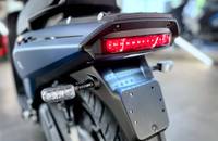 Nahaufnahme des Heckbereichs eines Scooters mit rotem Rücklicht und grauem Verkleidungsteil.