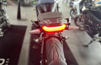 Heckansicht eines E-Motorrads mit leuchtendem Rücklicht und breitem Reifen.