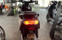 Weiße E-Scooter in Dreiviertelansicht vor einem Showroom-Hintergrund.