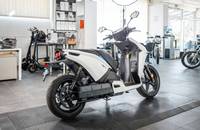 Seitenansicht eines weißen elektrischen Scooters in einem Showroom.
