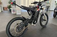 Seitenansicht eines weißen E-Motorrads, das in einem Showroom steht.