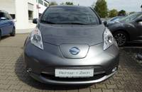 Frontansicht eines grauen Nissan Leaf Elektroautos, geparkt vor einem Autohändler.