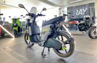 Der graue Elektroroller wird seitlich in einem gut beleuchteten Showroom präsentiert.