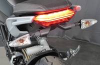 Nahaufnahme des Heckbereichs eines Motorrads mit beleuchteter Rückleuchte und Blinker.