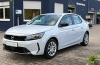 Außenansicht eines weißen Opel Corsa, geparkt vor einem Autohaus.