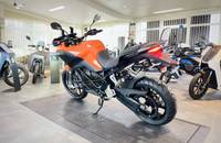 Seitenansicht eines orangefarbenen Elektro-Motorrads in einem Showroom.