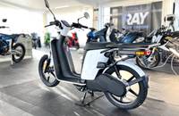 Seitenansicht eines weißen E-Scooters, der in einem Showroom steht. Das Fahrzeug hat einen modernen, geschwungenen Aufba