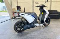 Seitenansicht eines weißen elektrischen Scooters auf einem gefliesten Boden.