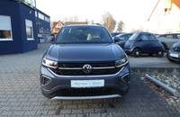 Frontansicht eines VW T-Cross in Rauchgrau Metallic vor einem Autohändler.