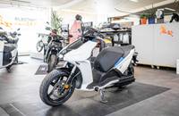 Weiße Elektro-Roller in Dreiviertelansicht in einem Showroom.