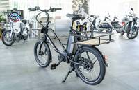 Außenansicht eines schwarzen E-Lastenrads auf einem Fliesenboden in einem Autohaus.