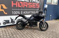 Ein schwarzes Elektro-Motorrad steht vor einem Autohaus mit der Aufschrift "Electric Horses".