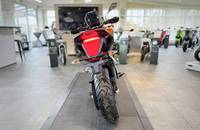 Orangefarbenes E-Motorrad steht in einem hellen Showroom.