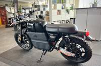 Seitenansicht eines schwarzen Elektro-Motorrads (RGNT TURBO) in einem Showroom.