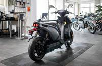 Seitenansicht eines grauen E-Scooters in einem Autohaus.