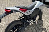 Seitenansicht eines silbernen E-Motorrads (ZERO 2) auf einem gepflasterten Boden.