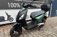 Außenansicht eines Piaggio Scooters in Grün-Schwarz vor einem Autohaus.