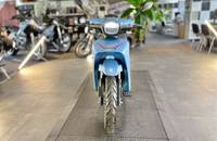 Frontansicht eines hellblauen elektrischen Scooters in einem Showroom.