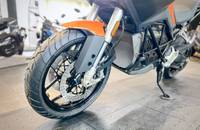 Frontansicht eines orangefarbenen E-Motorrads mit großen Felgen und sichtbarer Federung.