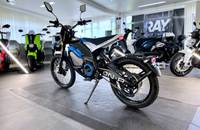 Blaues Motorrad (VMOTO ON-R) in einer hellen Ausstellungshalle.