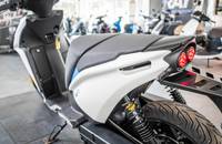 Frontansicht eines weißen E-Scooters mit Scheinwerfern und Federung.
