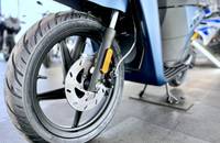 Nahaufnahme des Hinterrads eines blauen Motorrollers. Details sind Reifen, Bremsscheibe und die Heckverkleidung.