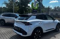 Außenansicht eines weißen KIA Sportage auf einem Autohausparkplatz.