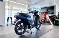 Seitenansicht eines dunkelblauen Elektrorollers in einem hellen Showroom eines Fahrzeughändlers.