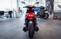 Heckansicht eines grauen E-Motorrads in einem Showroom.